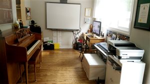 [Image of a music studio with a piano on the left, a Smart Board directly ahead, and a computer, keyboard, and printer/scanner to the right.]